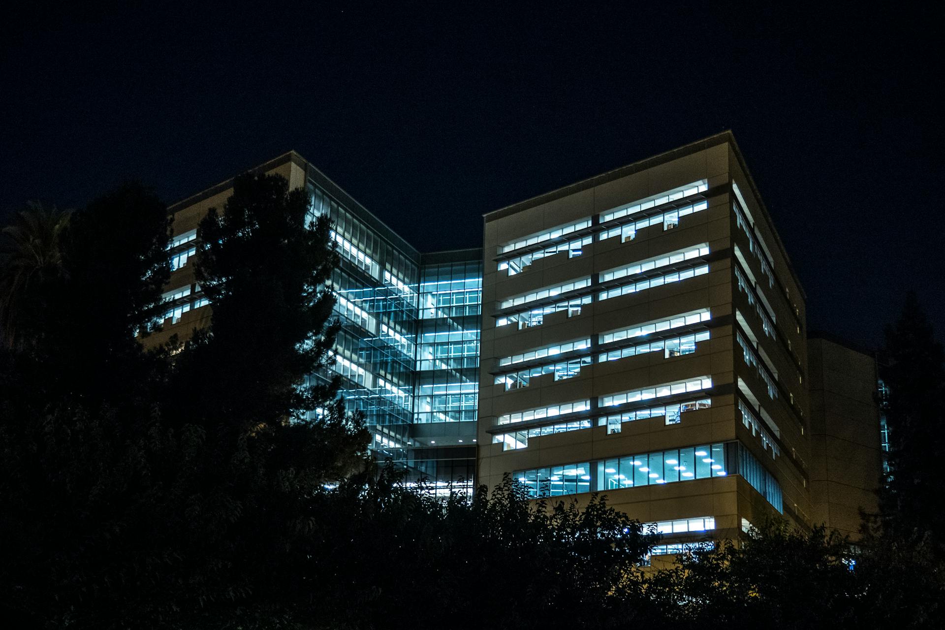 A contemporary office building lit up against the night sky, showcasing its modern architecture.