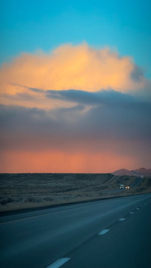 A highway with clouds in the sky and a car driving