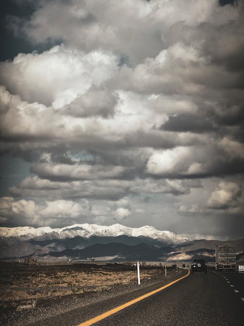 A road with clouds and mountains in the background