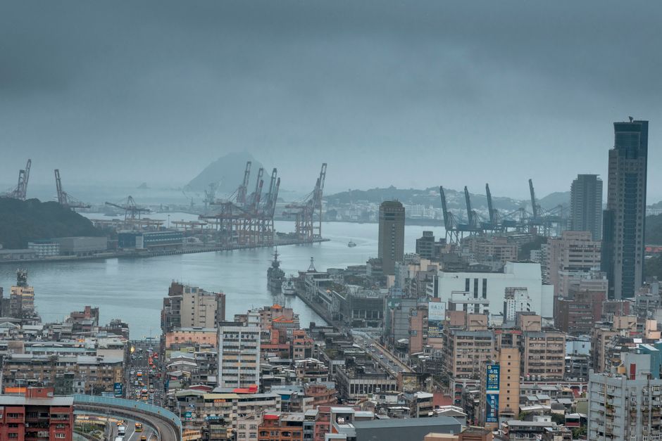Aerial view of Keelung Harbor showcasing urban sprawl and cranes under cloudy skies.