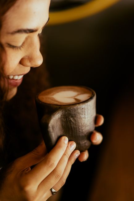 A joyful moment with a woman savoring a cappuccino with froth art. Close-up capture.