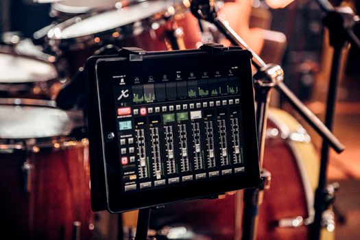 A digital audio mixer displayed on a tablet in a cozy indoor music studio setting.