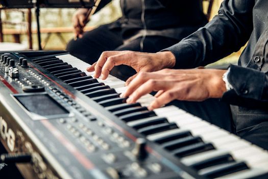 Hands playing a digital keyboard instrument indoors with selective focus.