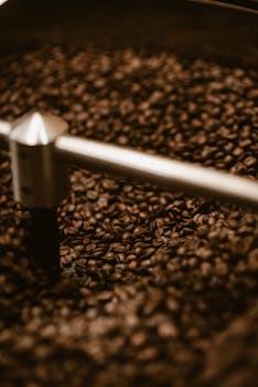 Close-up of freshly roasted coffee beans in an industrial coffee grinder, capturing rich aroma and texture.