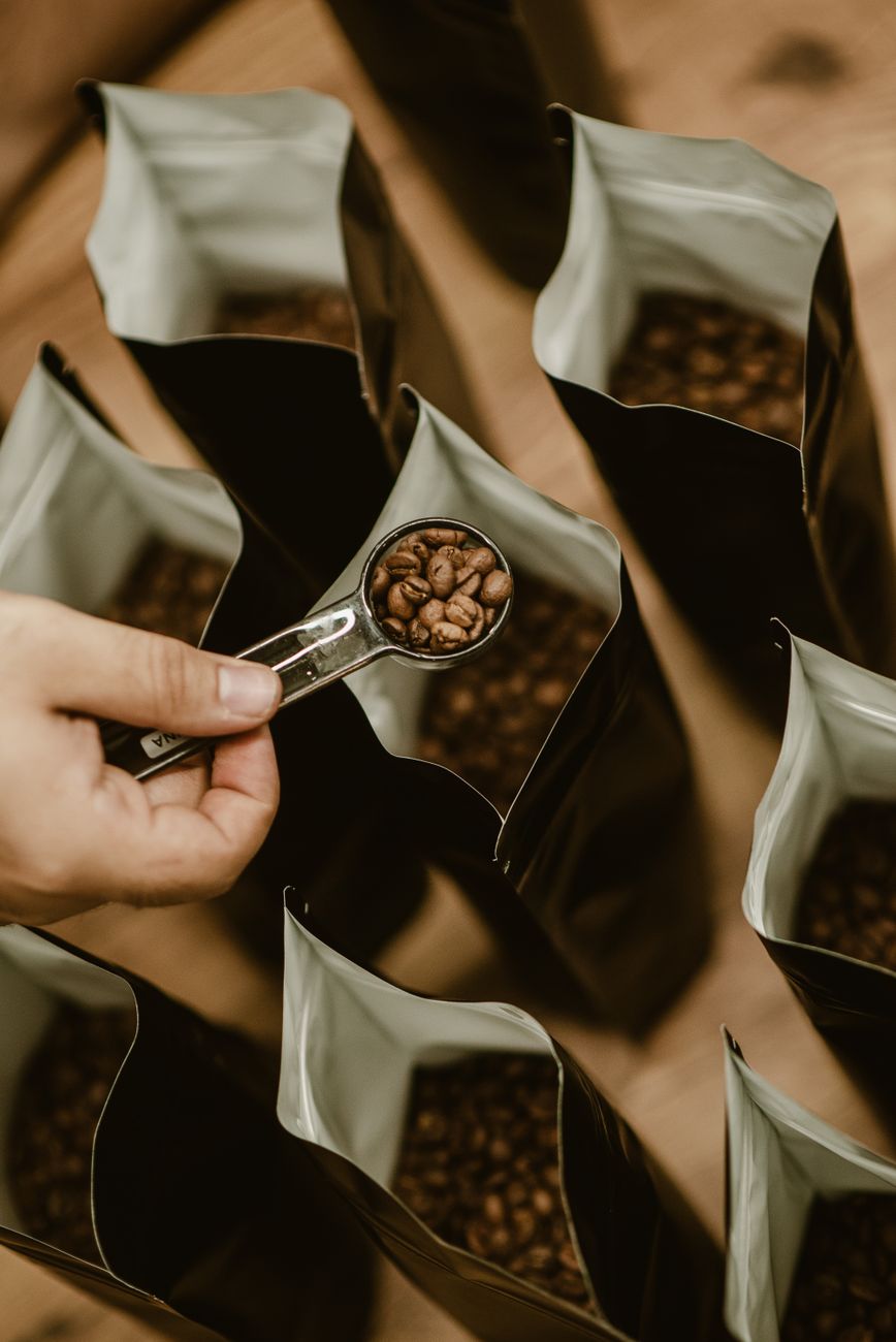 Freshly roasted coffee beans being scooped into a paper bag