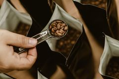 A person scooping coffee beans into bags, emphasizing fresh roasting and packaging.