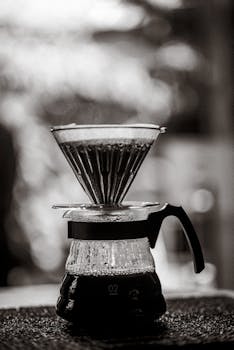 Classic pour over coffee maker with steaming coffee in black and white.