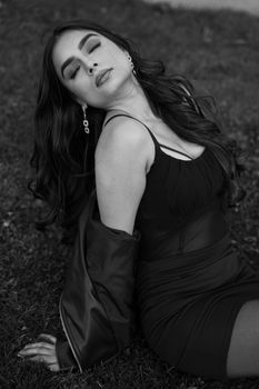 Sophisticated black and white portrait of a woman sitting with eyes closed, exuding elegance.
