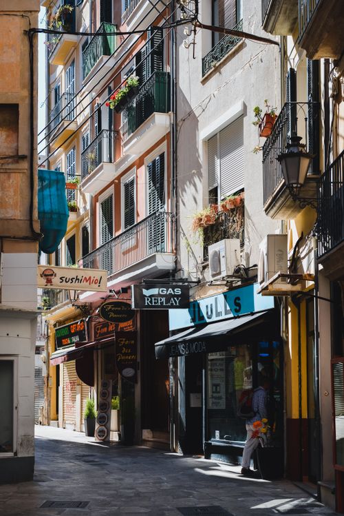 Free Vibrant, narrow alley in Palma de Mallorca with colorful facades and local shops. Stock Photo