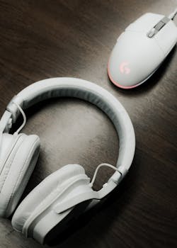 White headphones and computer mouse on a wooden table, showcasing modern electronics.