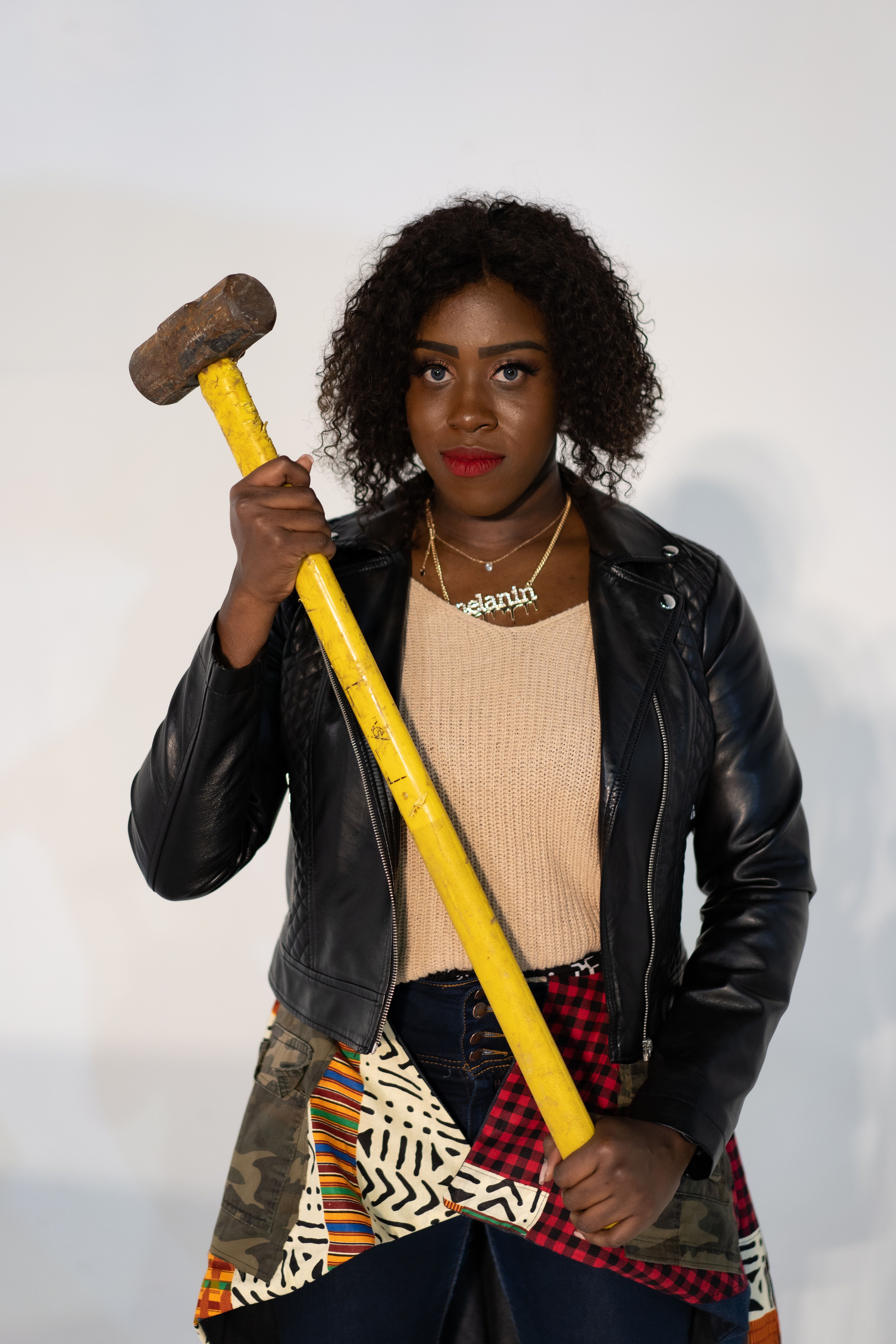 Strong portrait of a woman with a sledgehammer, showcasing empowerment and fashion.