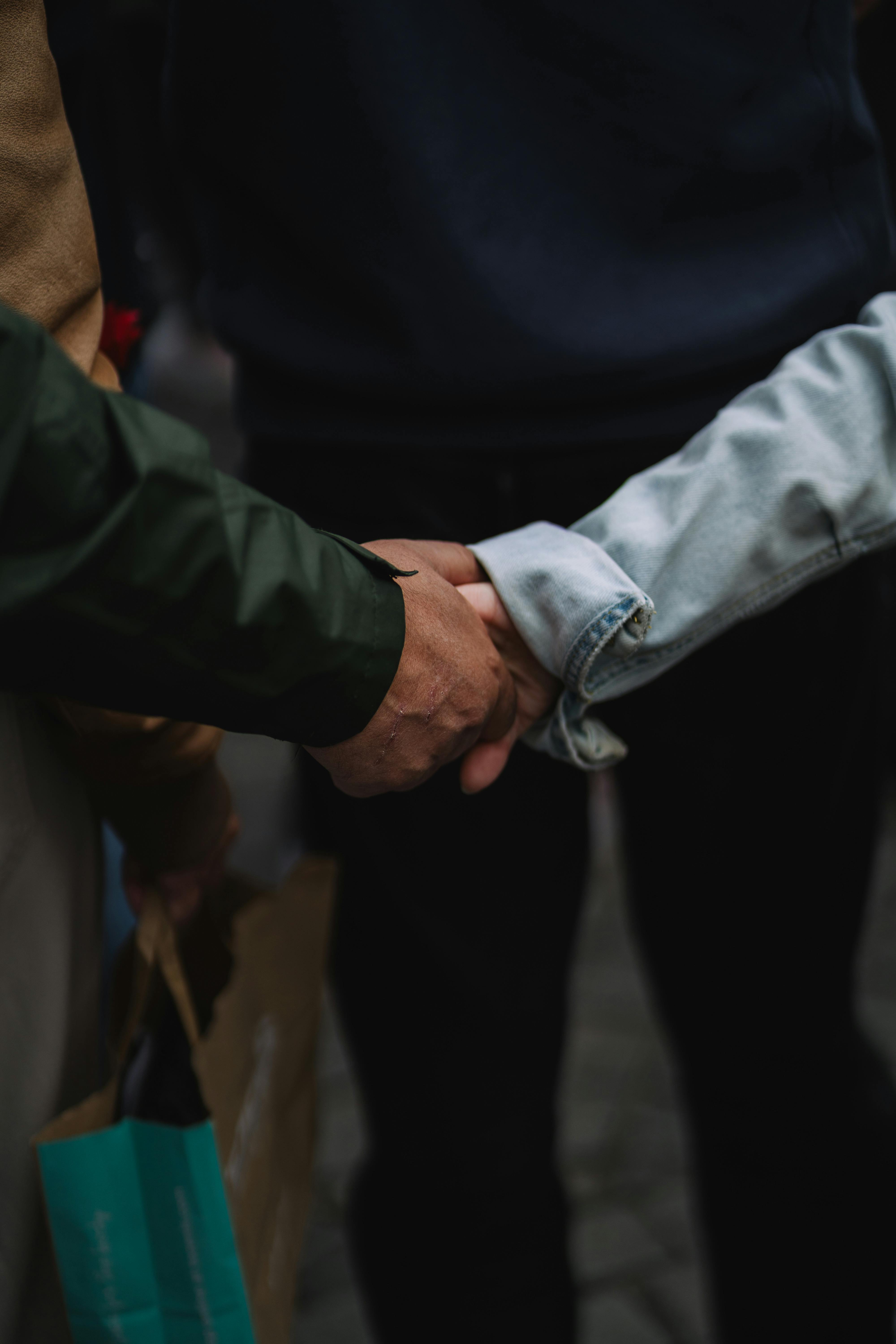 A close-up shot of two individuals shaking hands outdoors, signifying unity and agreement.