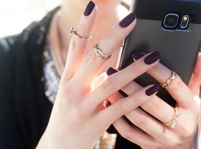 Manicured nails and rings holding a smartphone