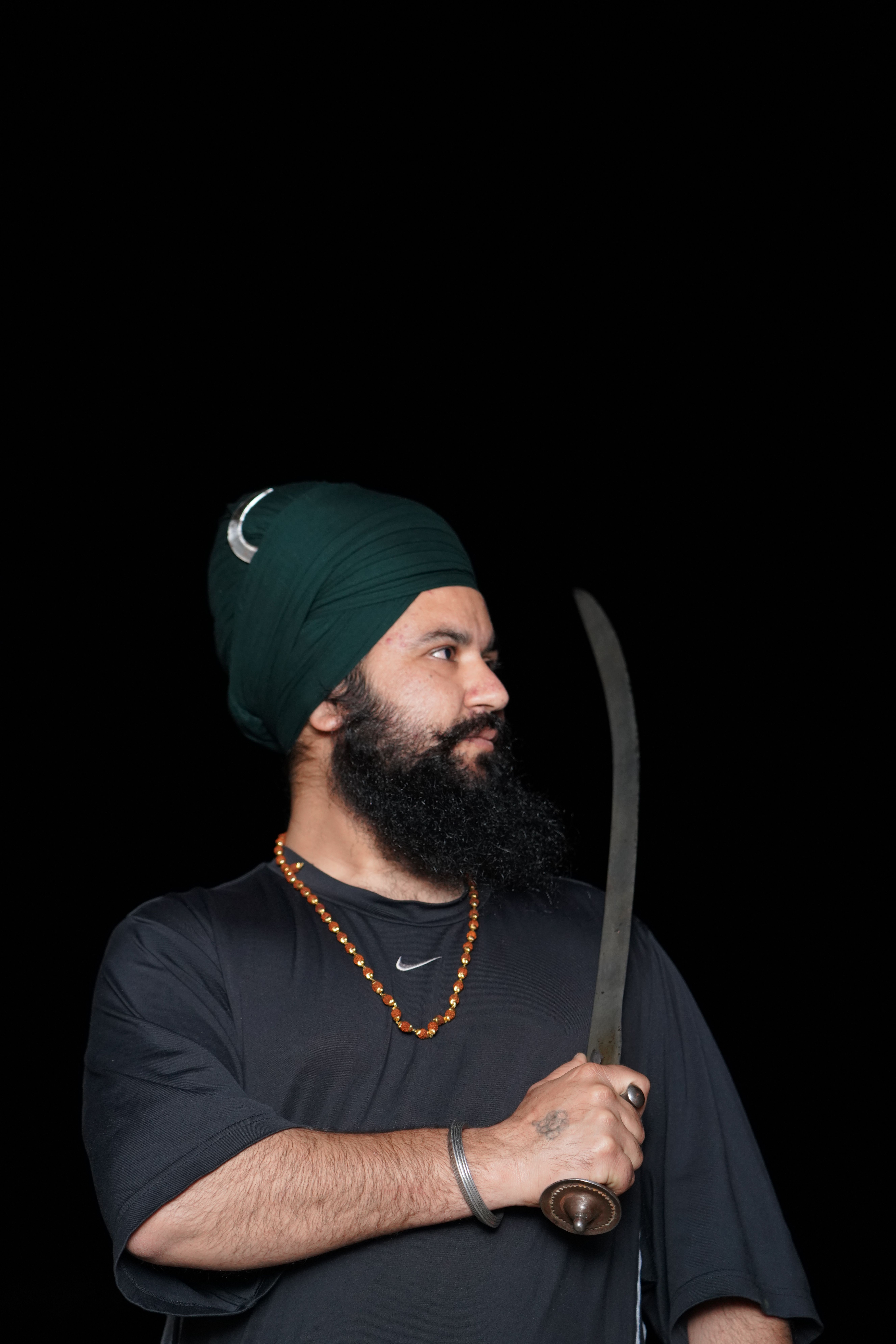 Sikh man with turban and sword, showcasing cultural attire and heritage.