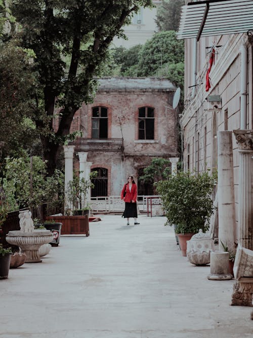 A woman in red jacket walking down a narrow alley