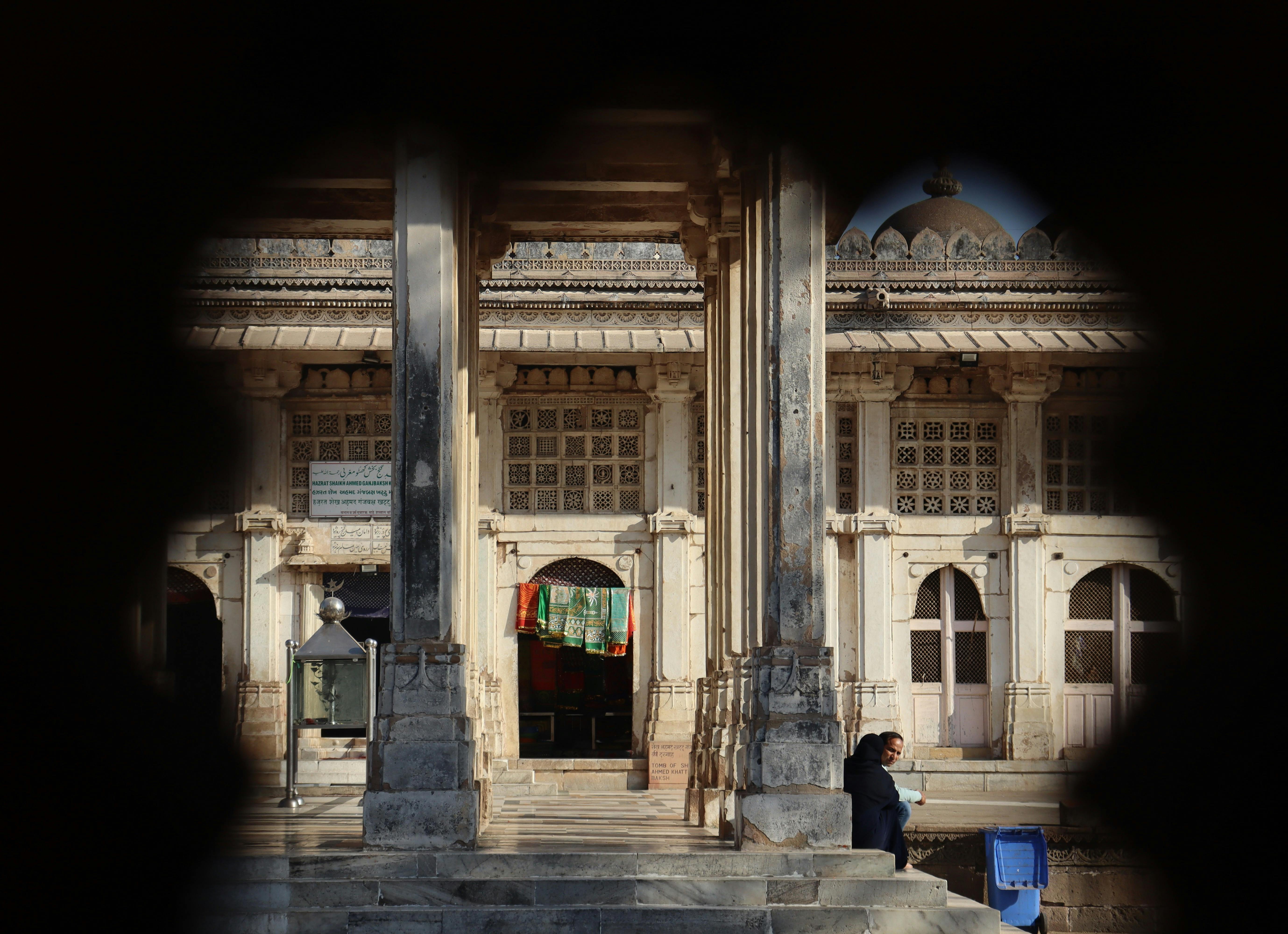A man is walking down a street in front of a building