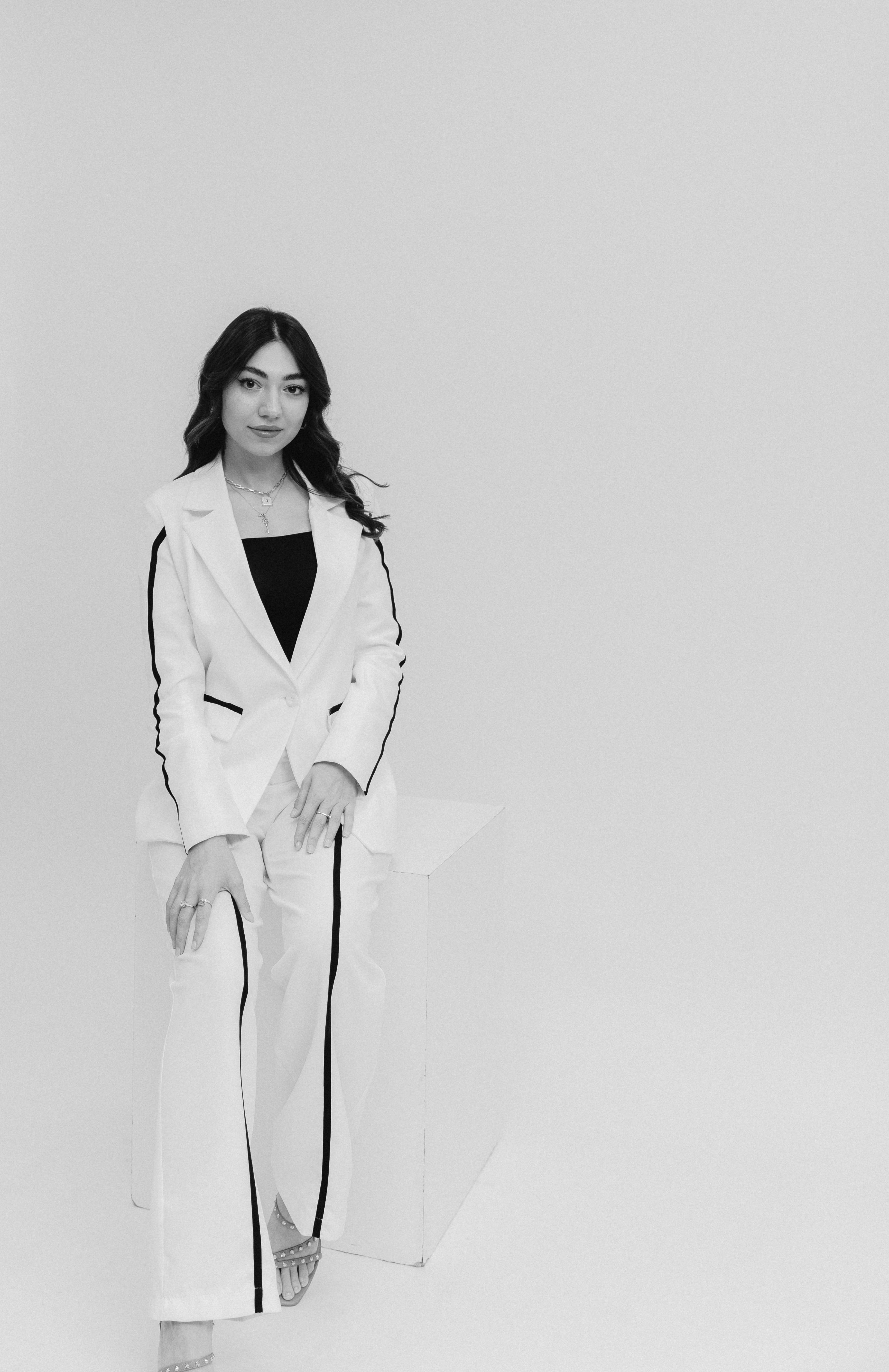 Black and white fashion photo of a woman in a blazer and pants during a studio shoot.