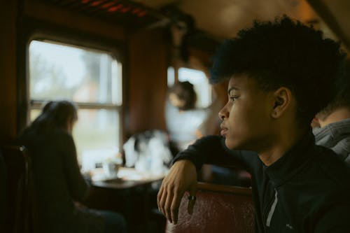 A young man sitting on a train looking out the window