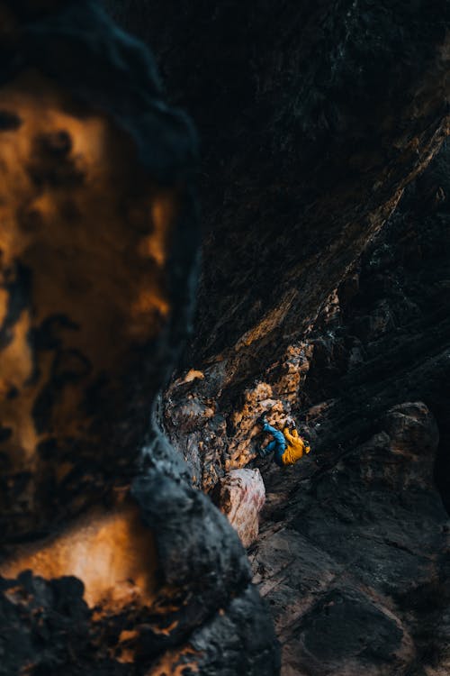 A person walking through a cave with a yellow jacket