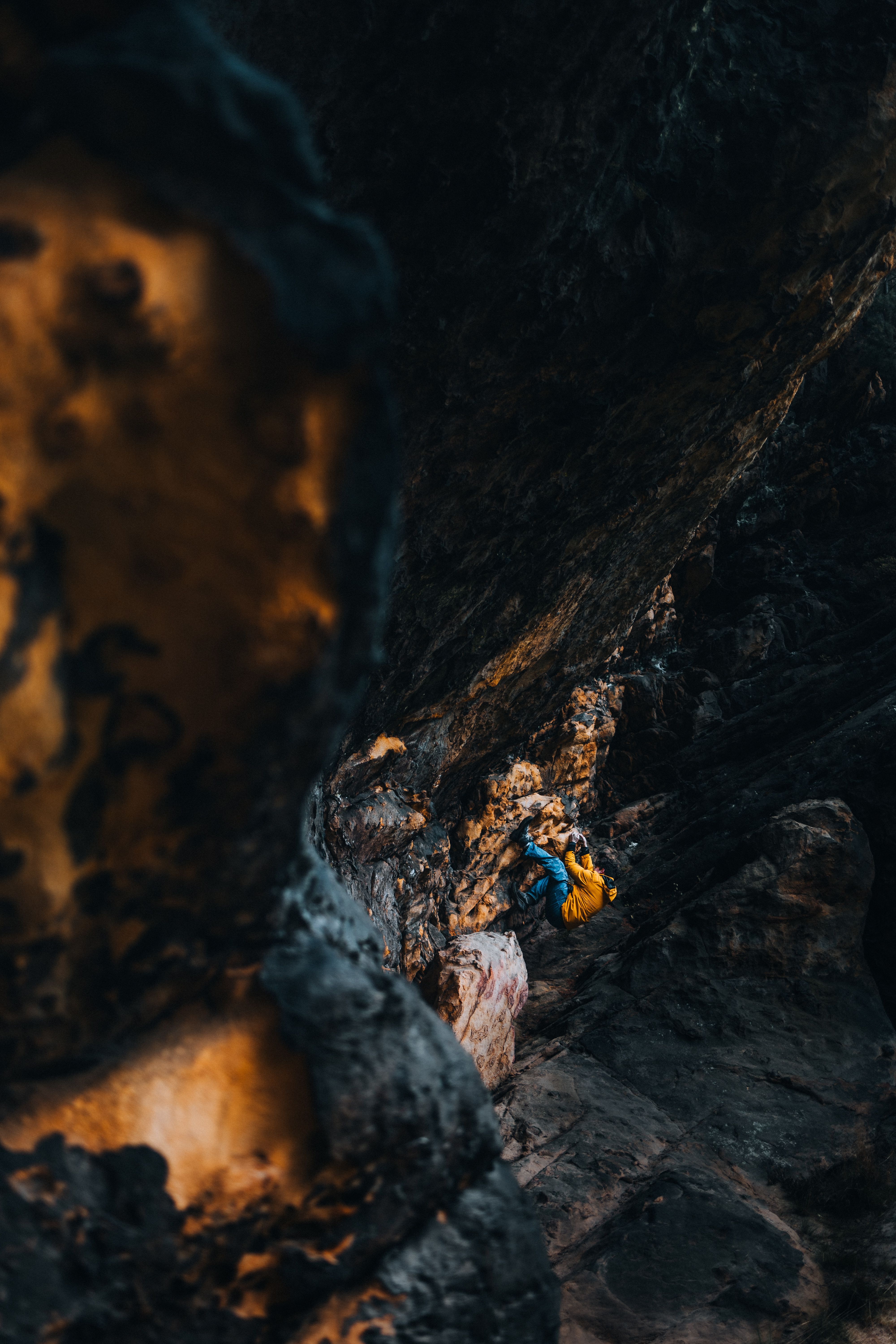 A person walking through a cave with a yellow jacket · Free Stock Photo