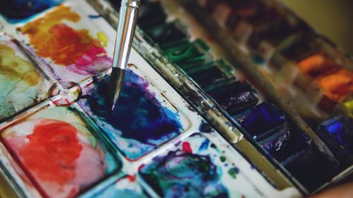 Free Close-up of a watercolor palette with vibrant paints and a paintbrush in action. Stock Photo