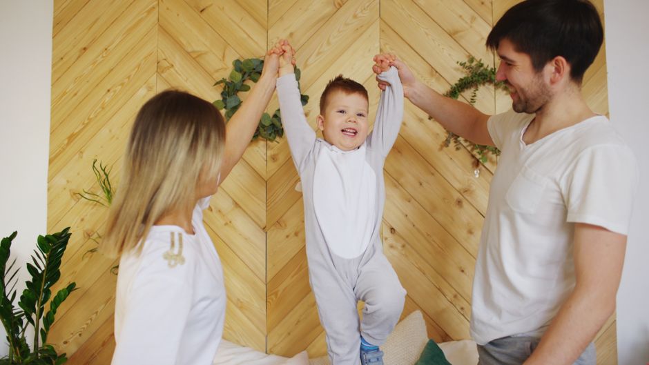 A joyful family moment with parents lifting their smiling child indoors.