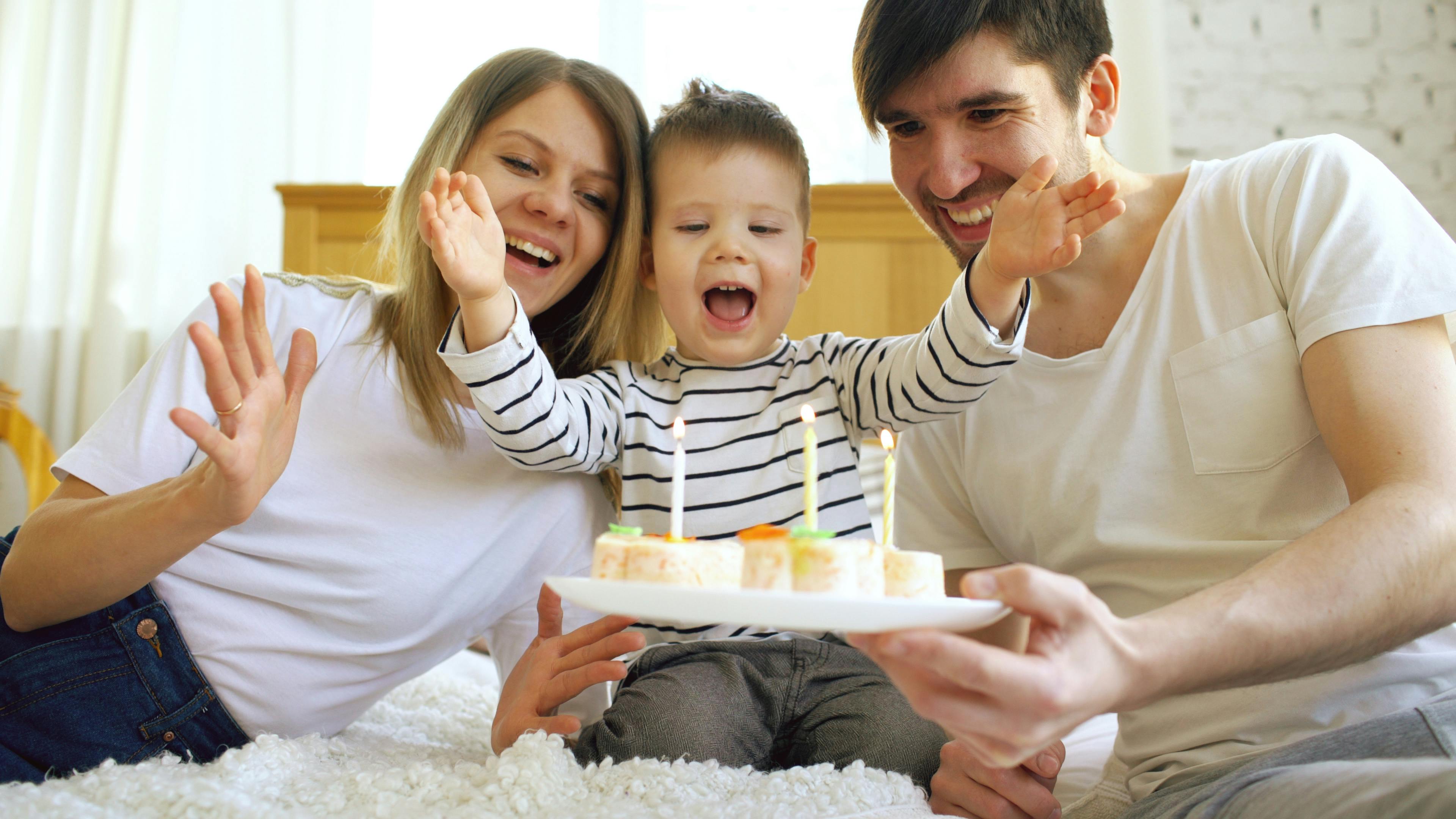 Smiling family celebrating their son birthday together before blowing candles on cake
