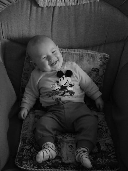 A baby smiling in a chair with mickey mouse ears