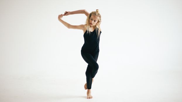 A young girl in a black leotard is doing a dance