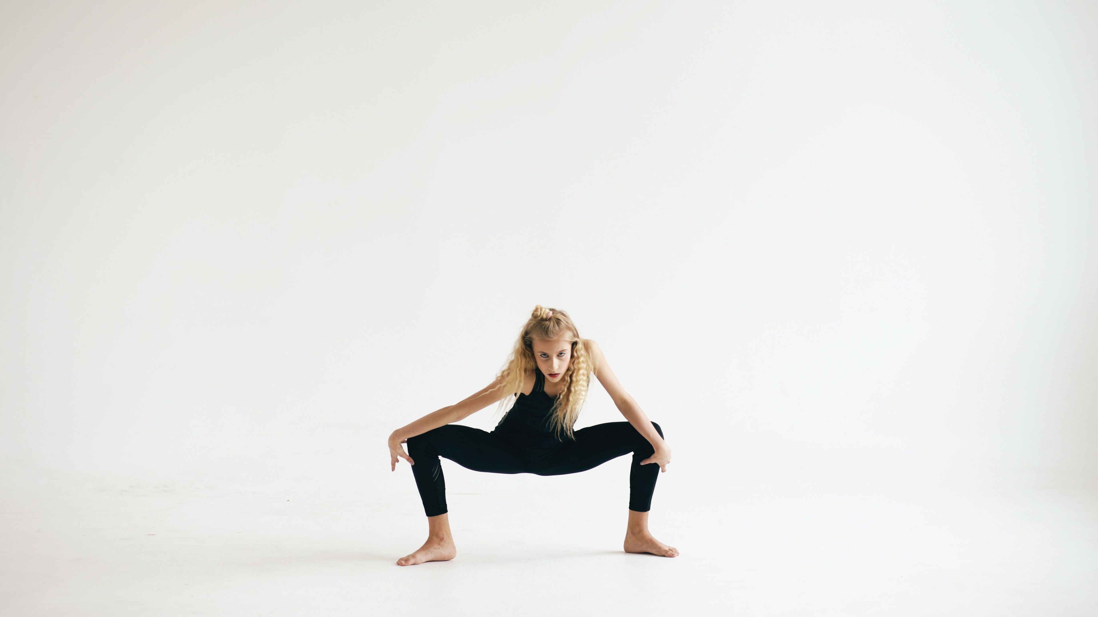 Young female dancer performs an expressive pose in a minimalist studio, showcasing agility and grace.