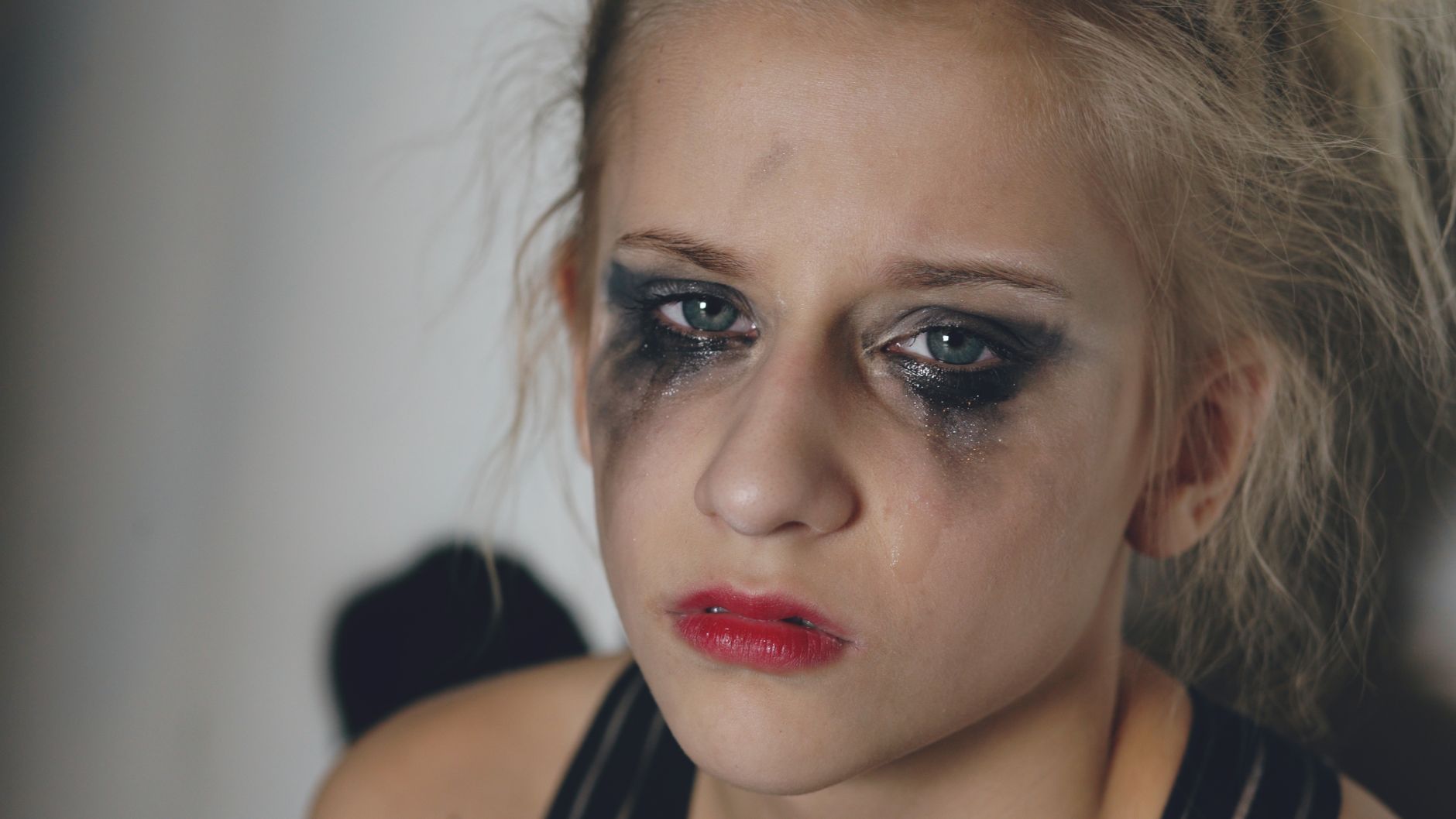 Close-up portrait of a woman with messy makeup and tears, conveying deep emotion.