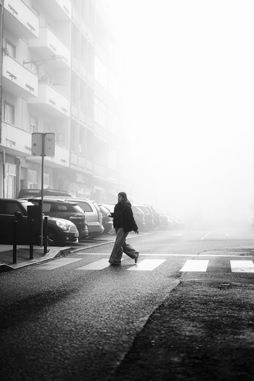 A person walking across a foggy street