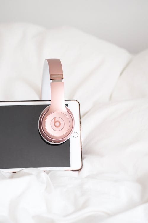 A pink headphones sitting on top of an iphone