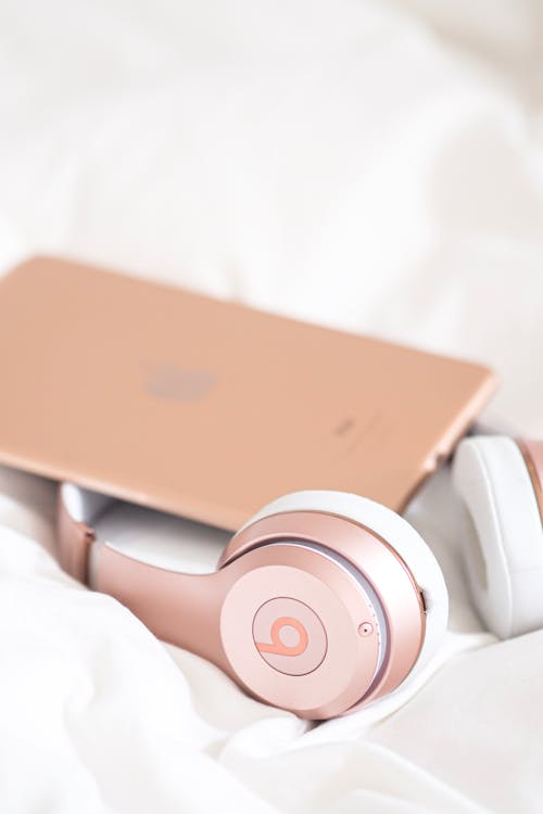 A pair of headphones and an ipad on a bed