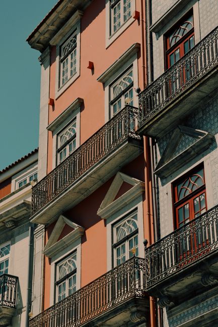 Sunny exterior of a classic 19th-century residential building in Porto, Portugal, featuring ornate balconies.