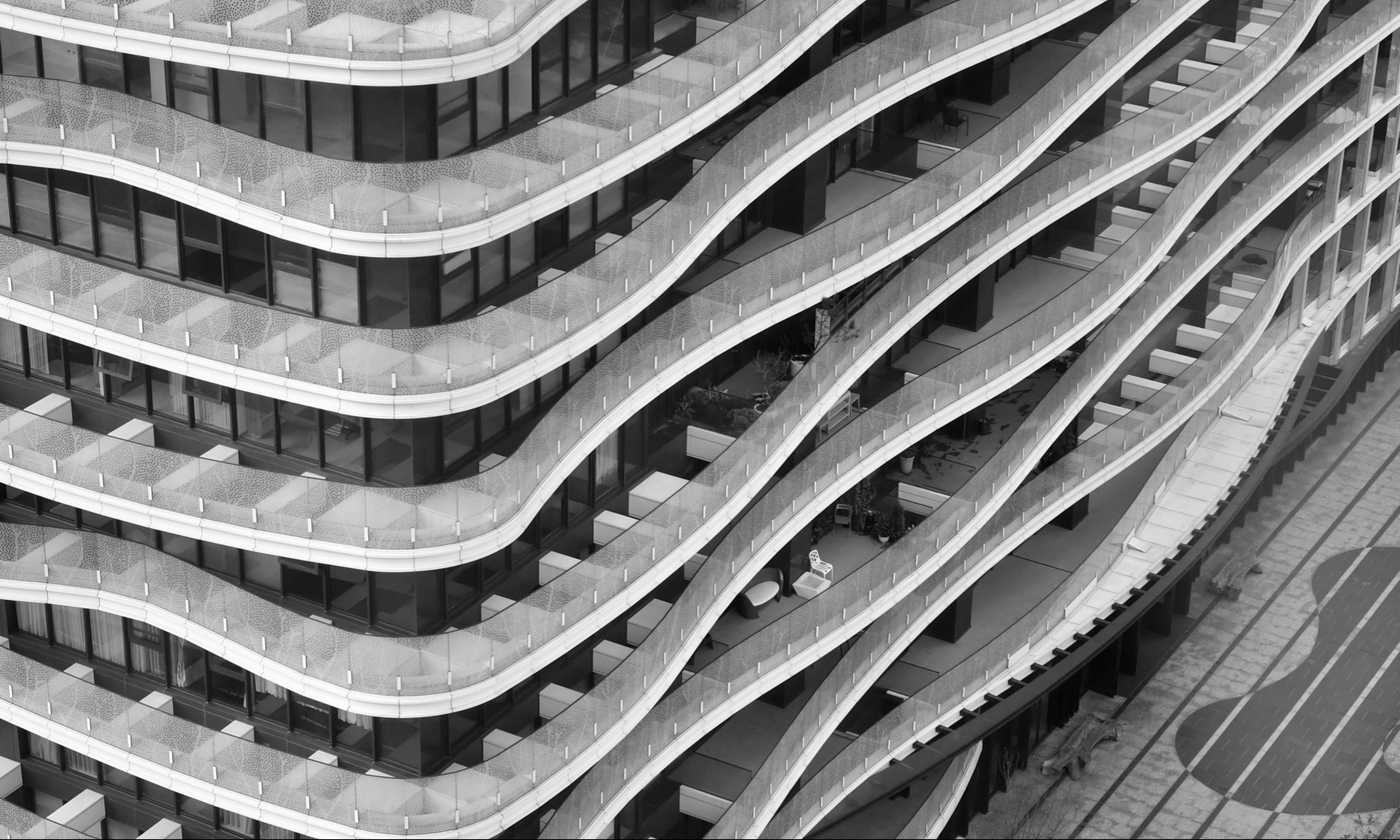Aerial shot of modern skyscraper with wave-like balconies in black and white.