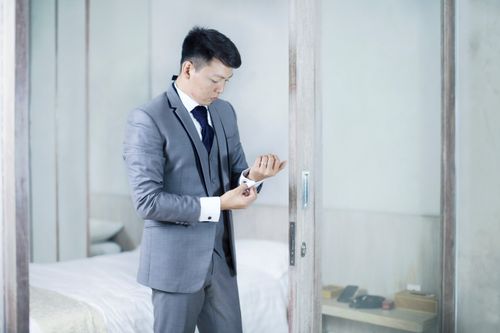 Free Professional man adjusting cufflinks in a modern gray suit, highlighting corporate style. Stock Photo