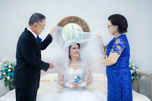 Woman in Wedding Dress Between Man in Formal Suit and Woman in Blue Dress