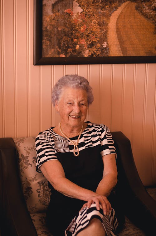 Smiling Woman Wearing Black and Grey Dress Sitting on Sofa