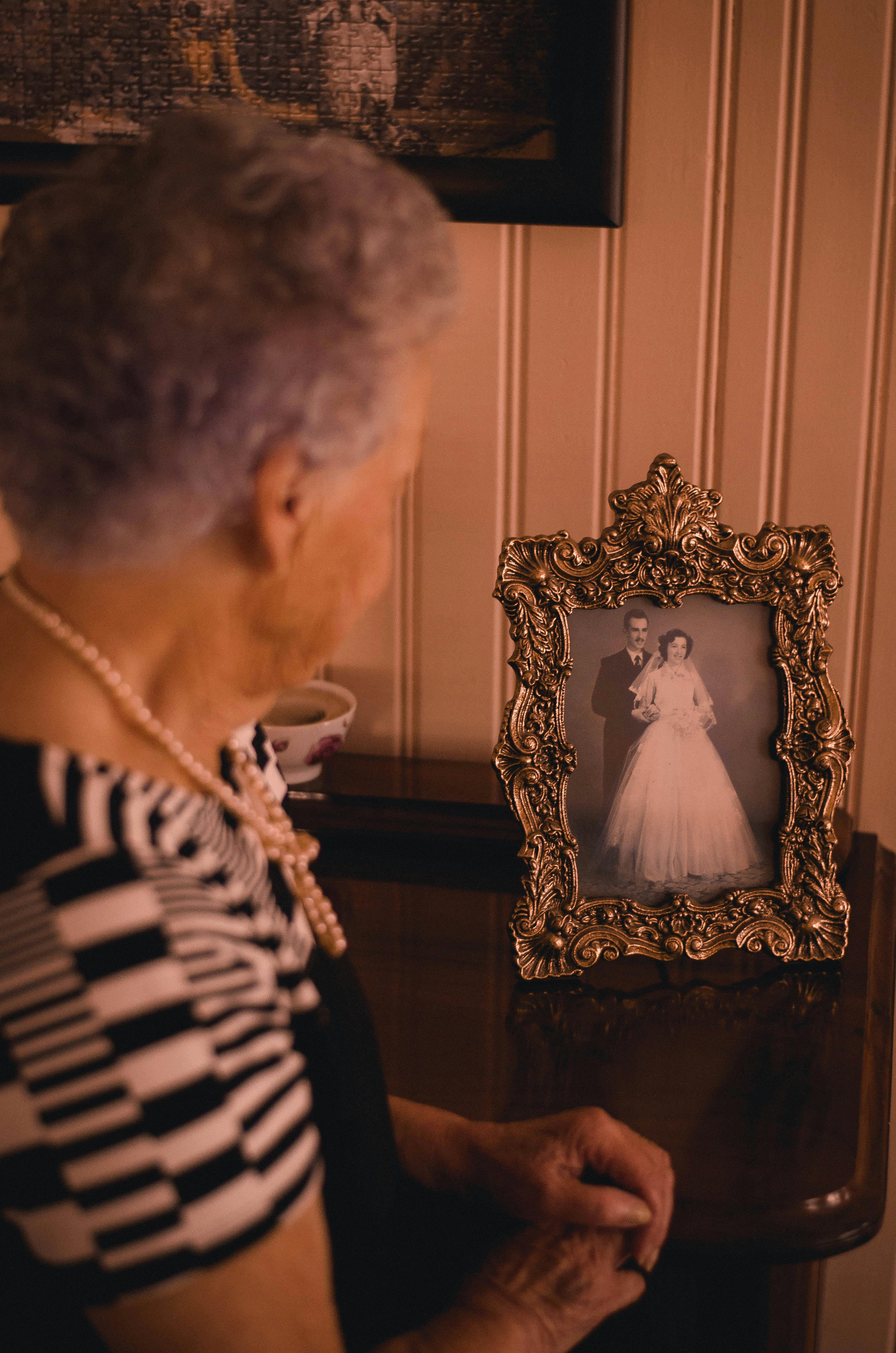 An old woman standing near the photo frame | Photo: Pexels