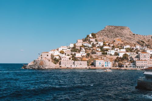 Free Scenic view of Idra, Greece showcasing rocky shoreline and classic architecture. Stock Photo