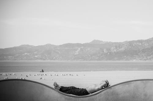 Free Man Lying on a Wall by the Water in a Mountain Valley in Black and White  Stock Photo