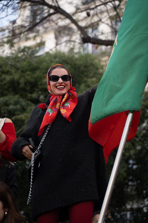 A woman in sunglasses and a scarf waving a green flag