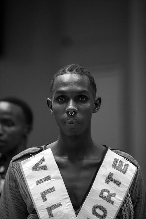 A man in a sash and crown is standing in front of a crowd