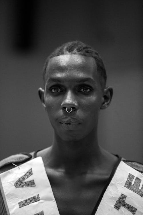A black and white photo of a man with a nose ring