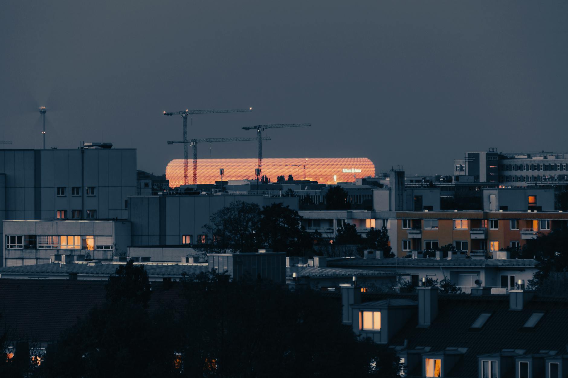 Illuminated Allianz Arena in Munich's urban skyline at night, showcasing modern architecture.
