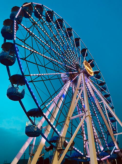 A ferris wheel at night with blue sky