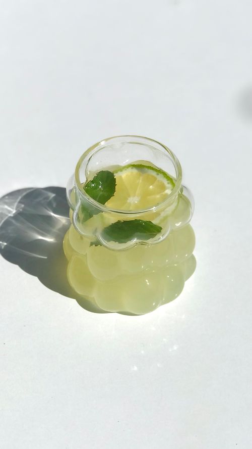 Free Aesthetic lime and mint infused water in a sculpted glass under bright sunlight, capturing a refreshing vibe. Stock Photo