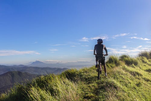 Man Riding Bicycle on Green Grass Field