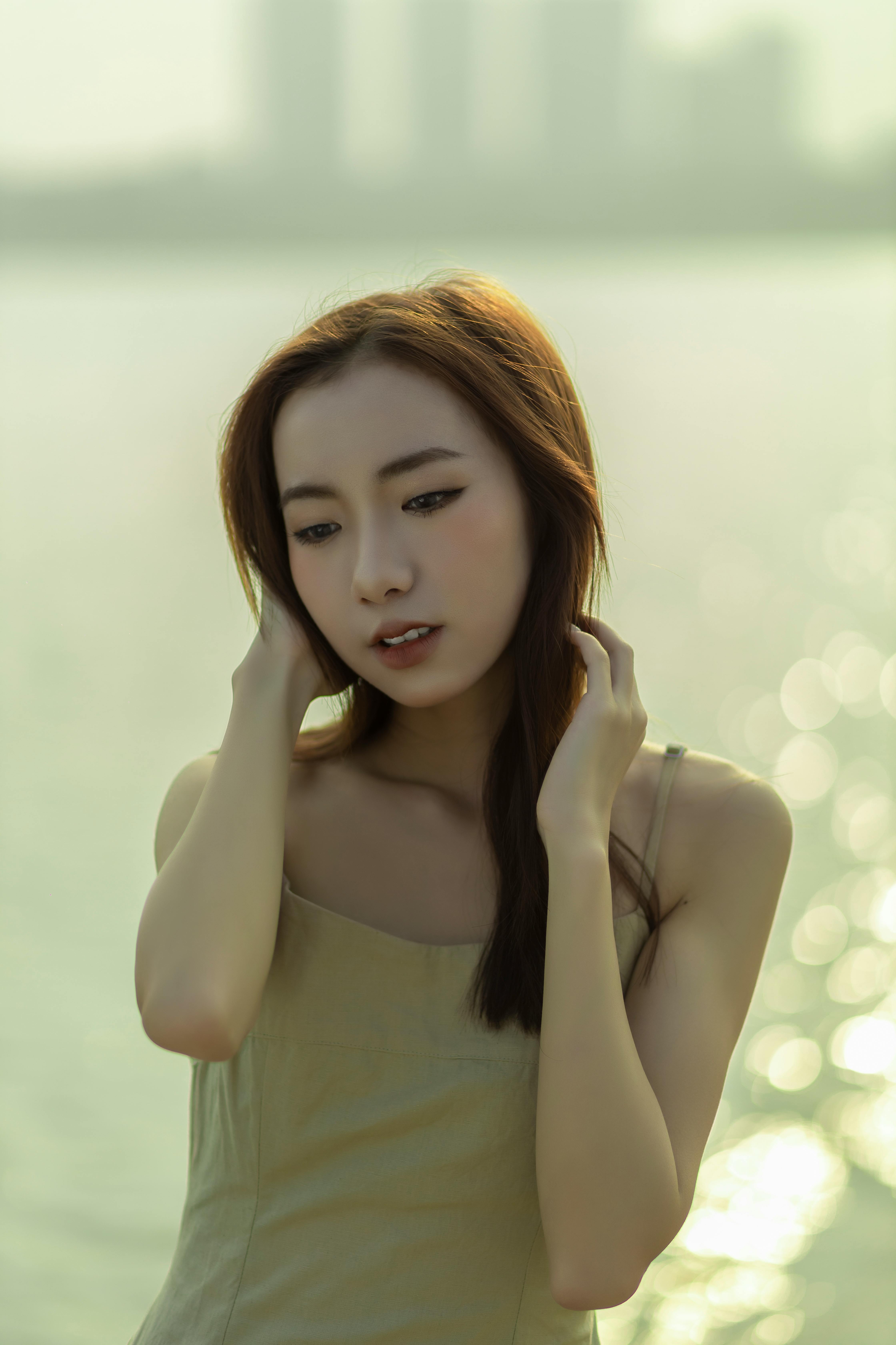 Young woman in a serene moment by tranquil waterfront under soft daylight.